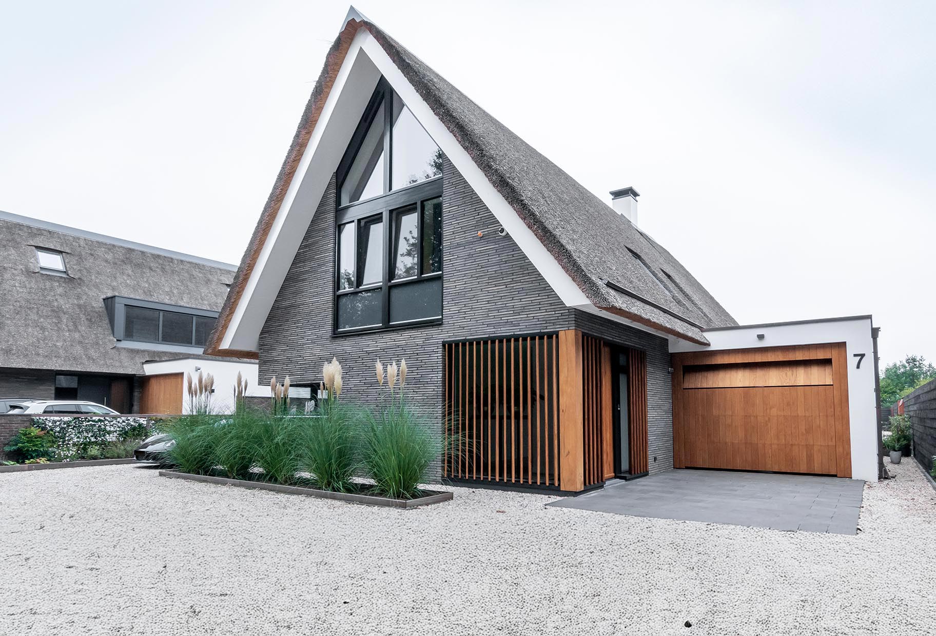 Moderne landelijke villa met een eikenhouten garagedeur, voordeur en gevelbekleding