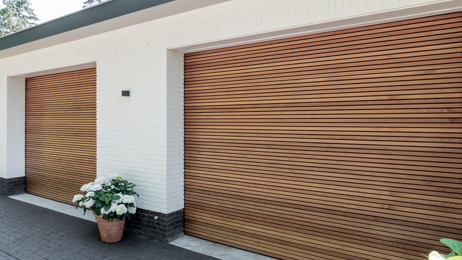 Horizontale houten sectionaaldeuren van Red Cedar bij wit gestucte woning