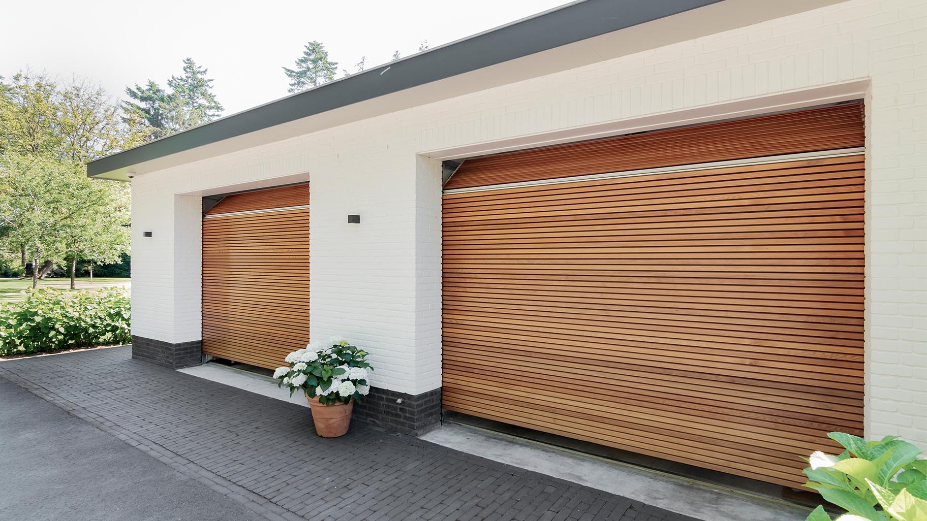 Horizontale houten sectionaaldeuren van Red Cedar bij wit gestucte woning