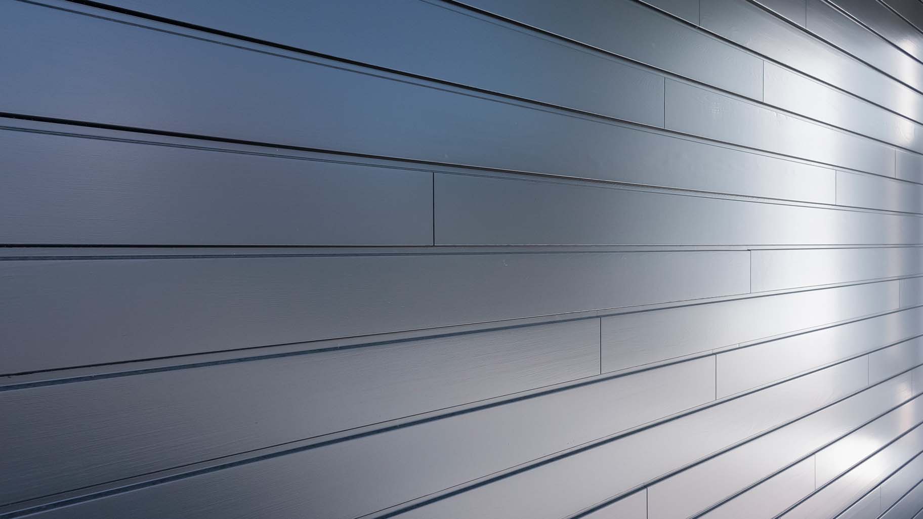 grijsblauw geschilderde garagedeur van Red Cedar is subtiel achter de gevel geplaatst