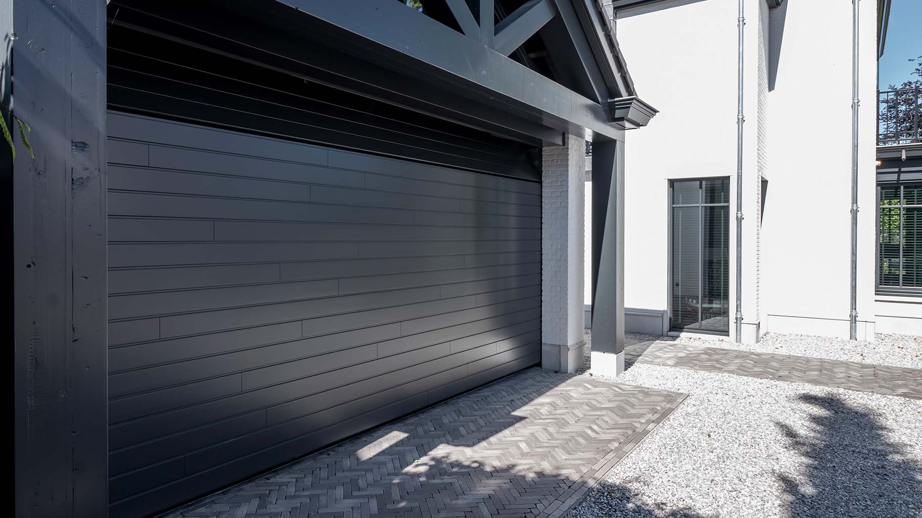 6 meter brede houten sectionaaldeur, uitgevoerd in Red Cedar en achter de dag geplaatst