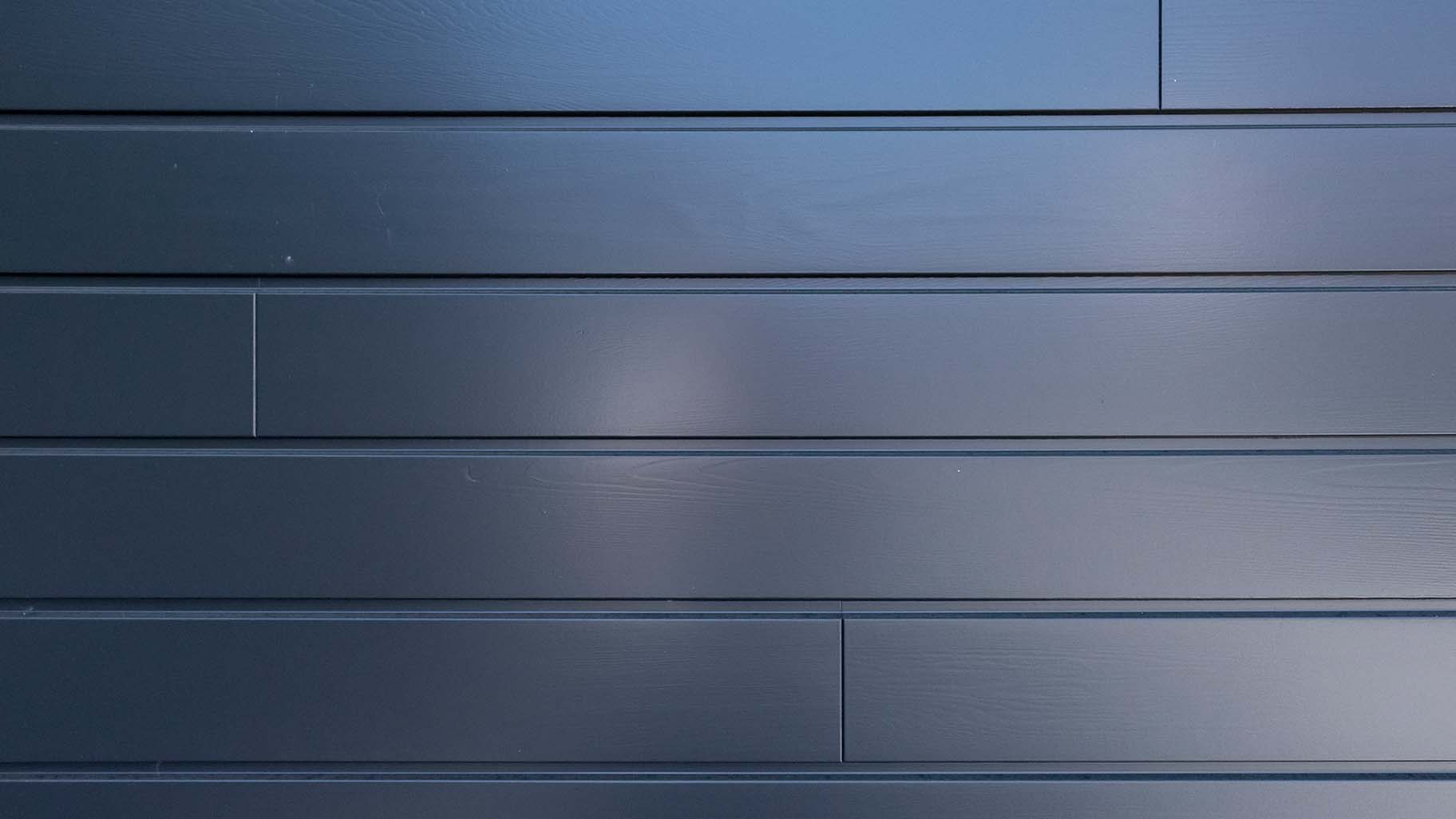 grijsblauw geschilderde garagedeur van Red Cedar is subtiel achter de gevel geplaatst