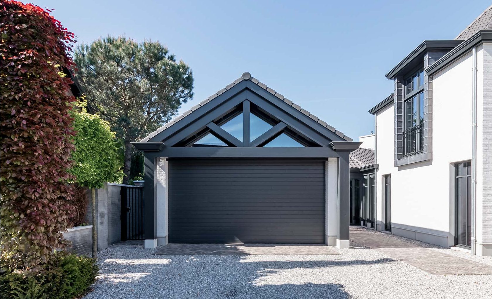 6 meter brede houten sectionaaldeur, uitgevoerd in Red Cedar en achter de dag geplaatst