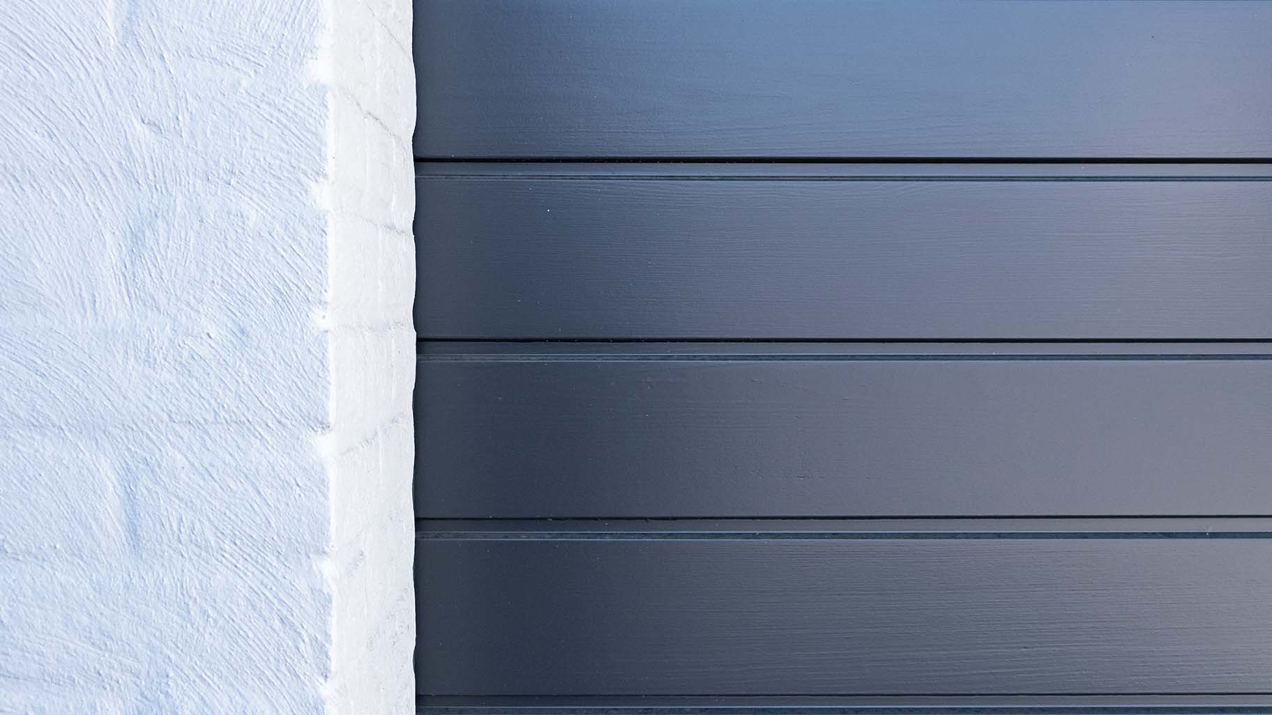 grijsblauw geschilderde garagedeur van Red Cedar is subtiel achter de gevel geplaatst