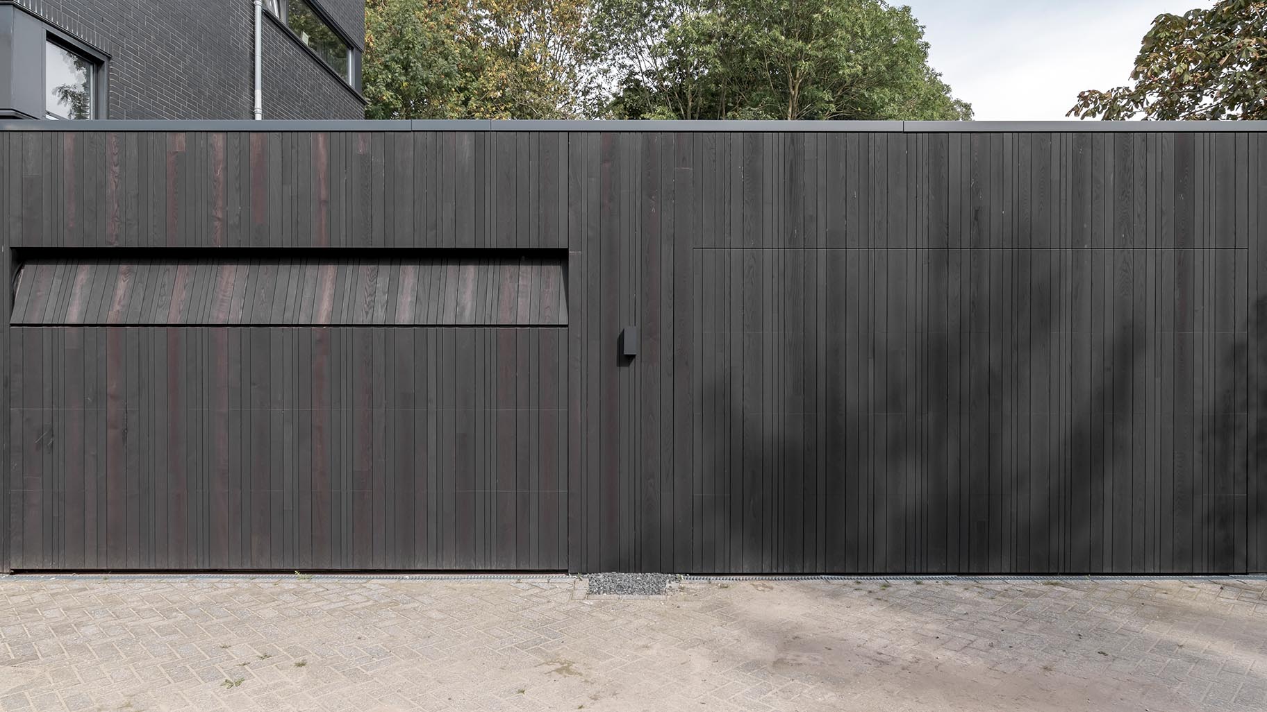 Donkere essenhouten garagedeuren verwerkt in de façade