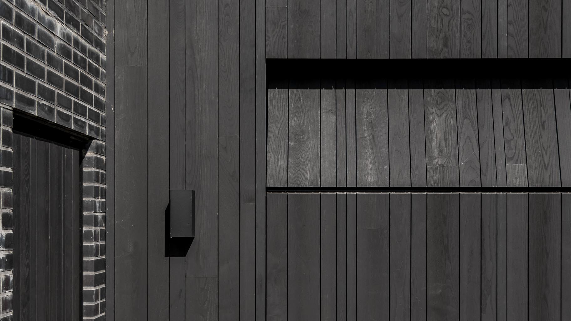 Donkere essenhouten garagedeuren verwerkt in de façade