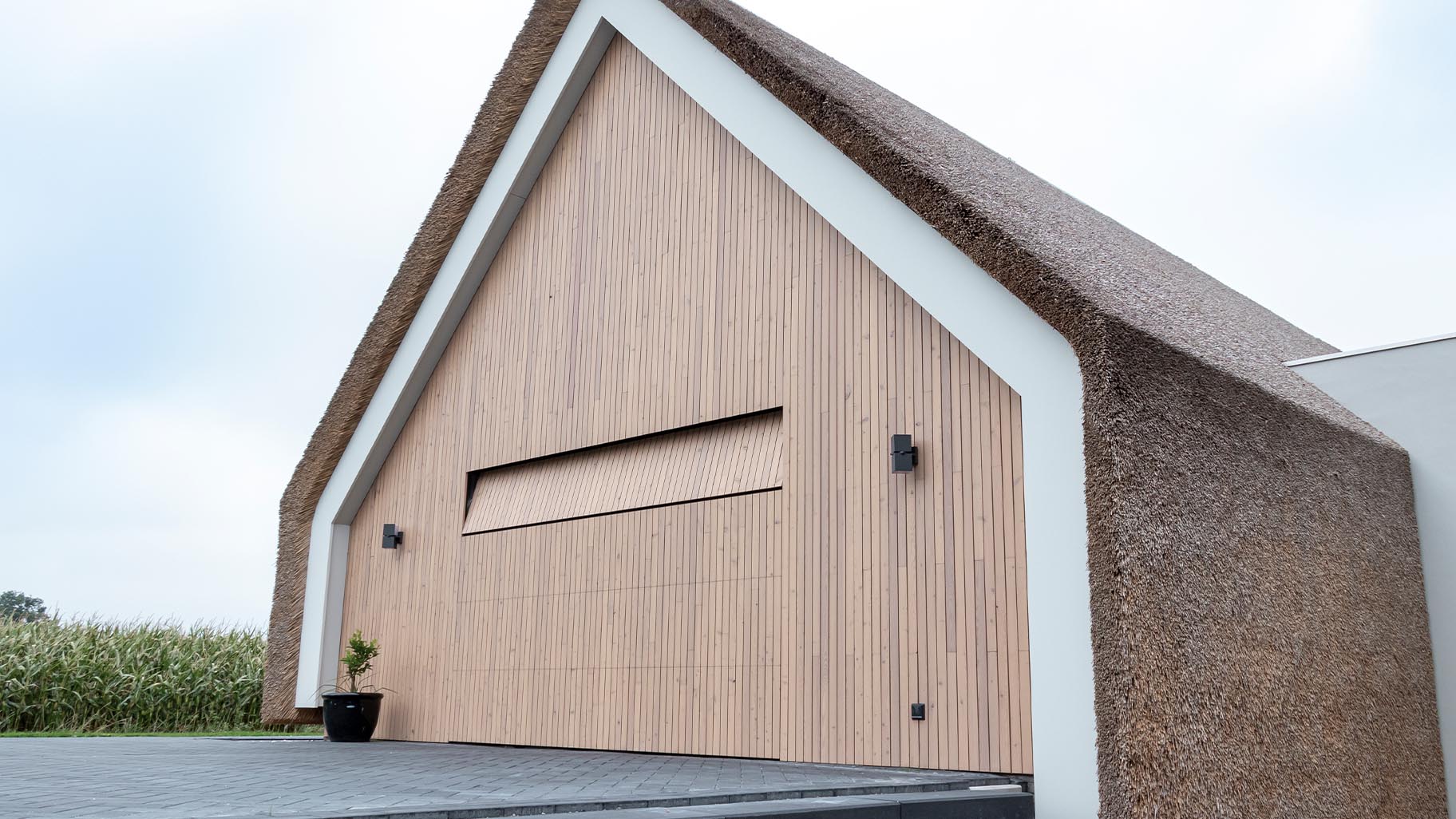 Houten sectionaaldeur naadloos opgenomen in de houten gevelbekleding