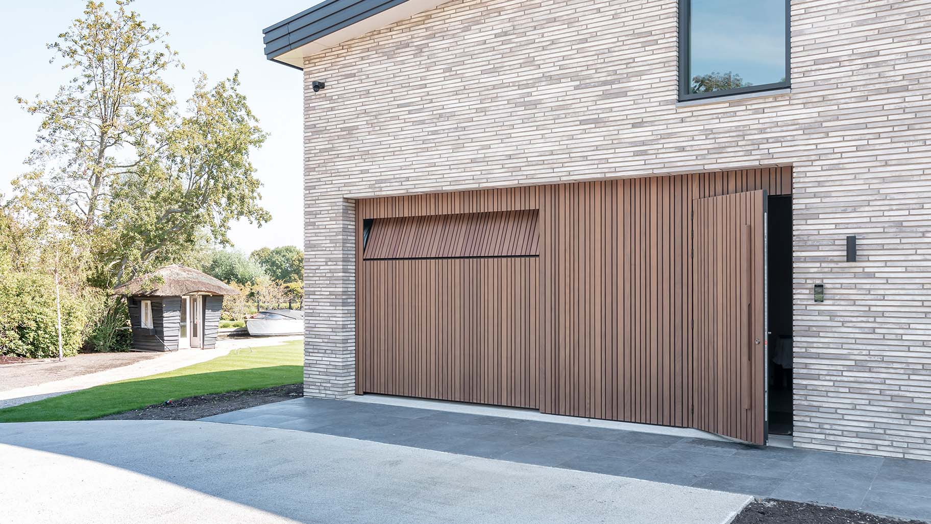 Houten taatsdeur en garagedeur geïntegreerd in de gevel