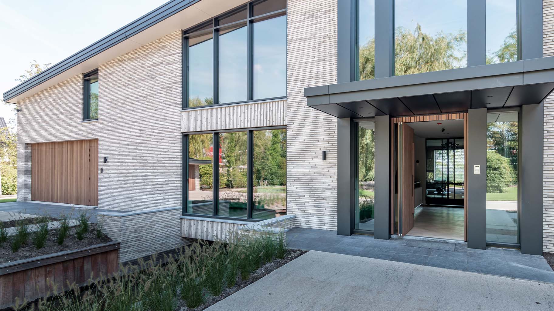 Houten taatsdeur en garagedeur geïntegreerd in de gevel