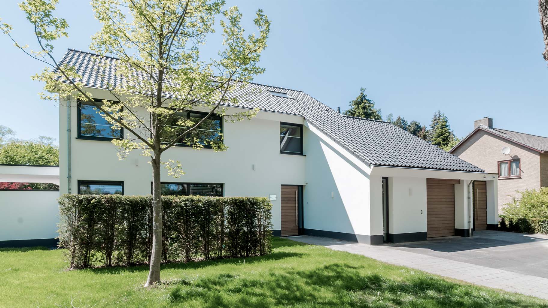 Houten voordeur en garagedeur in antracietkleurige gevel van moderne villa