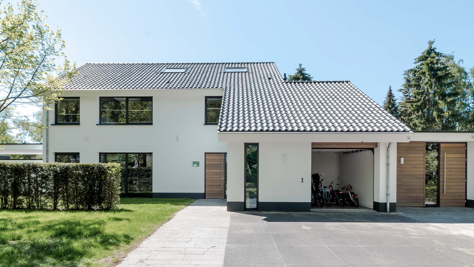 Houten voordeur en garagedeur in antracietkleurige gevel van klassieke villa