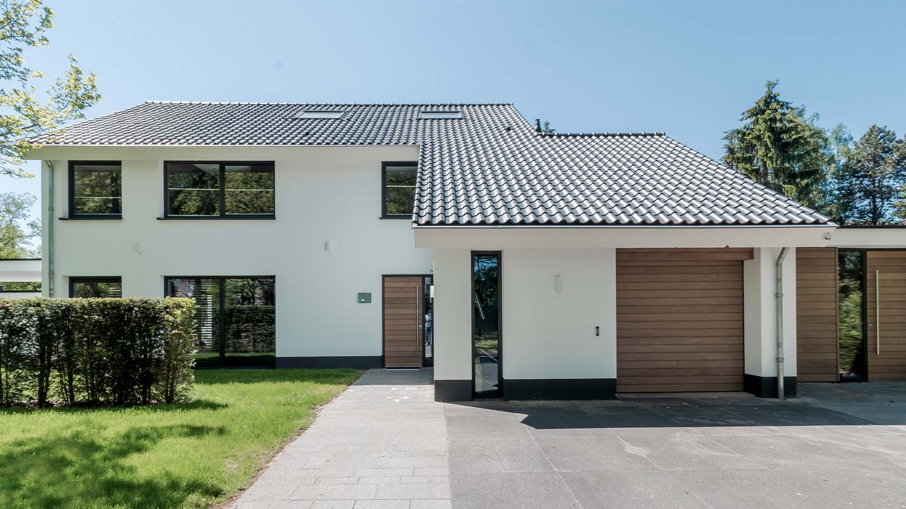 Houten voordeur en garagedeur in antracietkleurige gevel van klassieke villa
