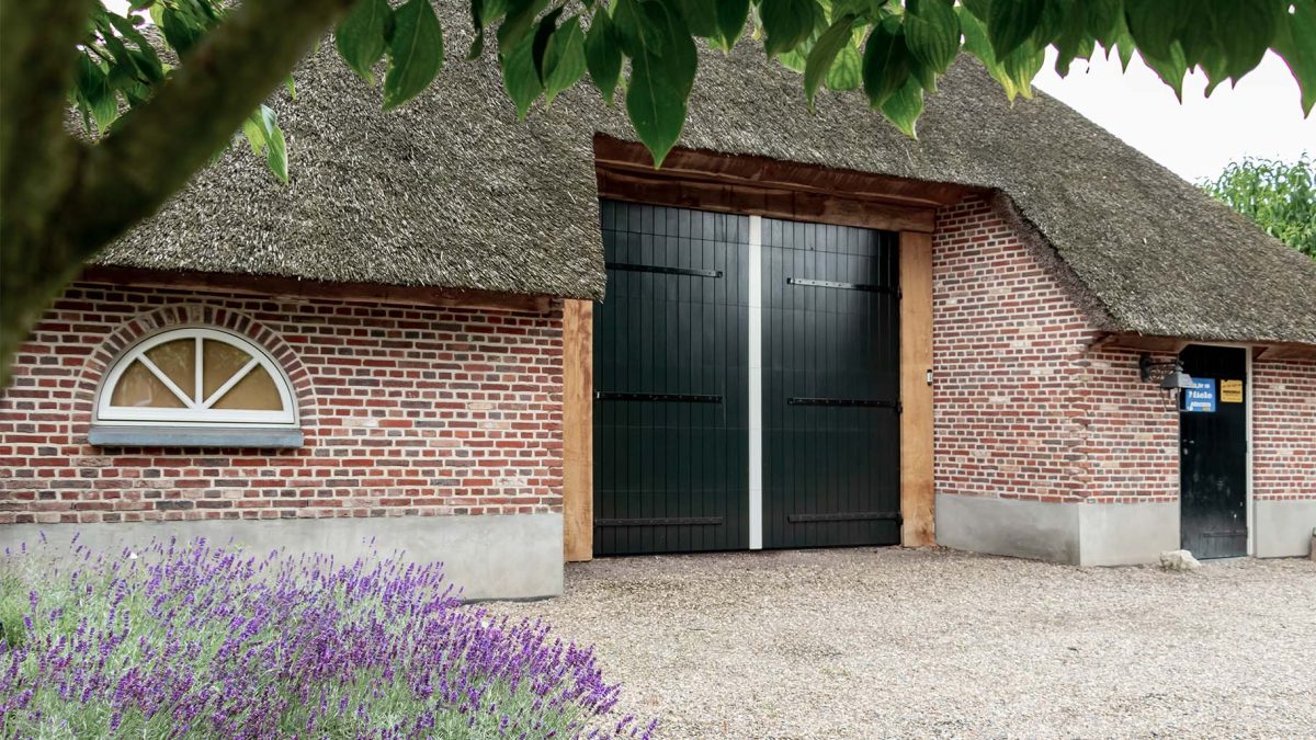 Boerderij met rieten dak en houten sectionaal garagedeur, passend bij landelijke uitstraling