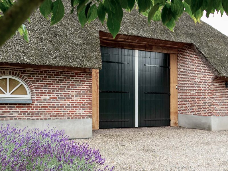 Boerderij met rieten dak en houten sectionaal garagedeur, passend bij landelijke uitstraling