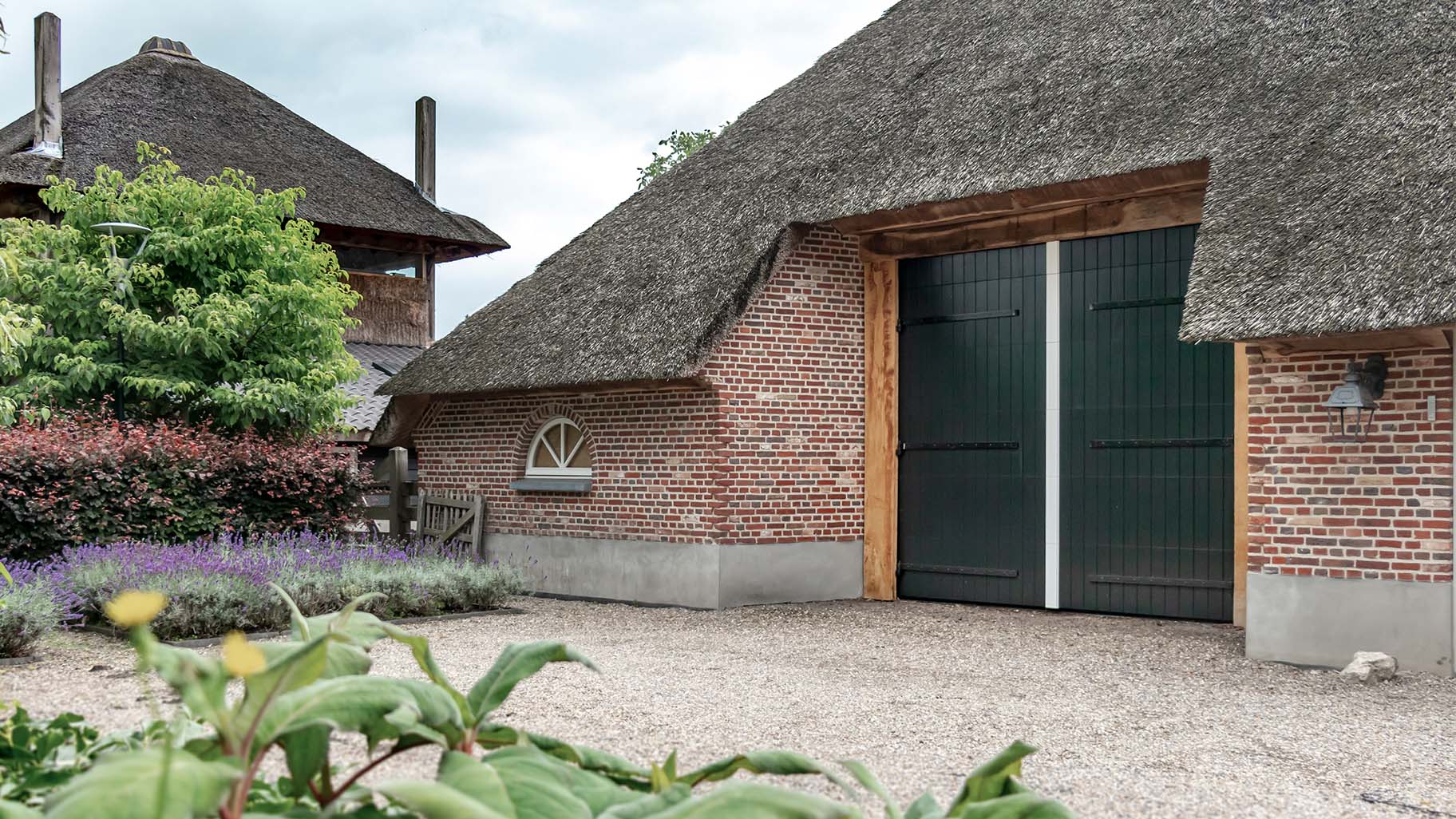 Boerderij met rieten dak en houten sectionaal garagedeur, passend bij landelijke uitstraling