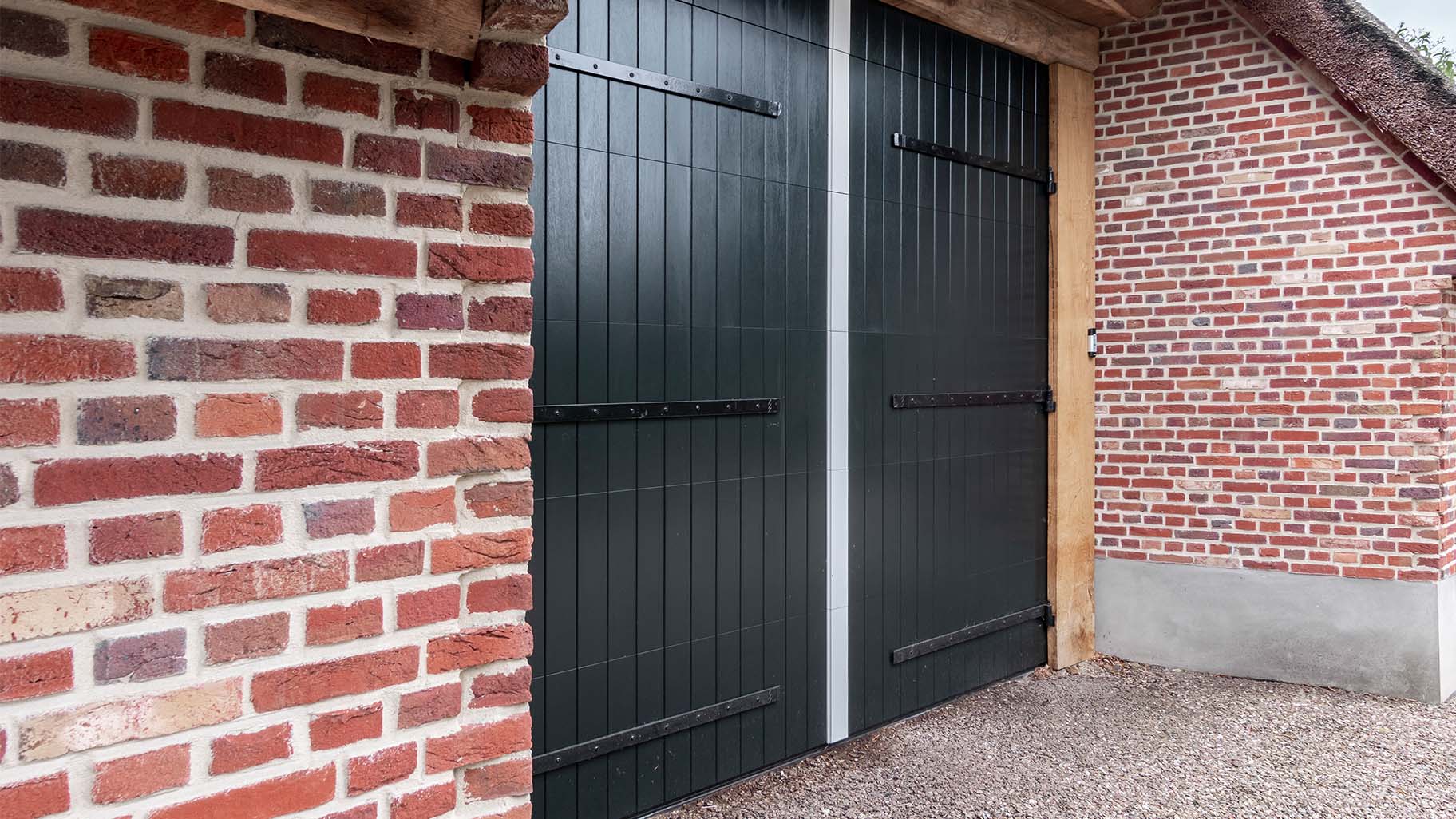 Boerderij met rieten dak en houten sectionaal garagedeur, passend bij landelijke uitstraling