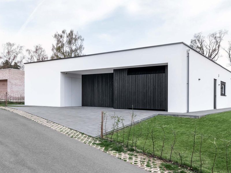 Strakke gevel met zwarte Shou Sugi Ban houten deuren, passend bij de minimalistische woning