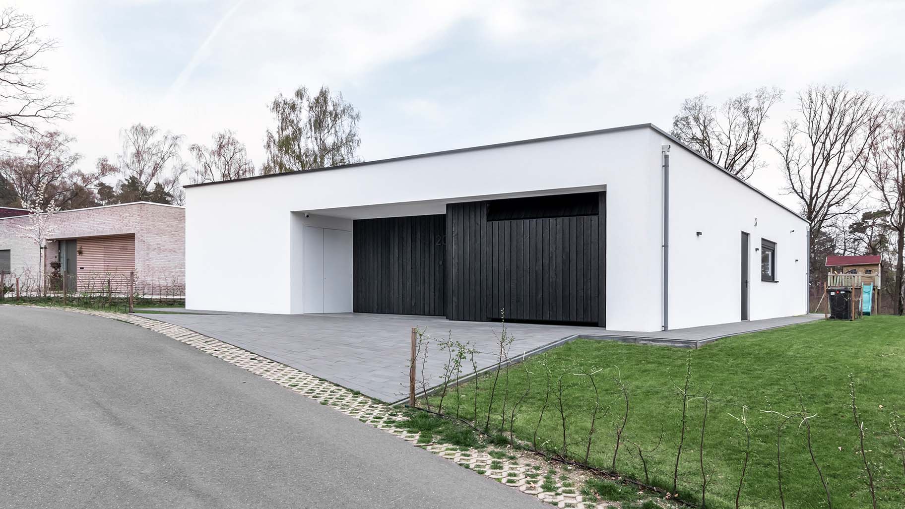 Strakke gevel met zwarte Shou Sugi Ban houten deuren, passend bij de minimalistische woning