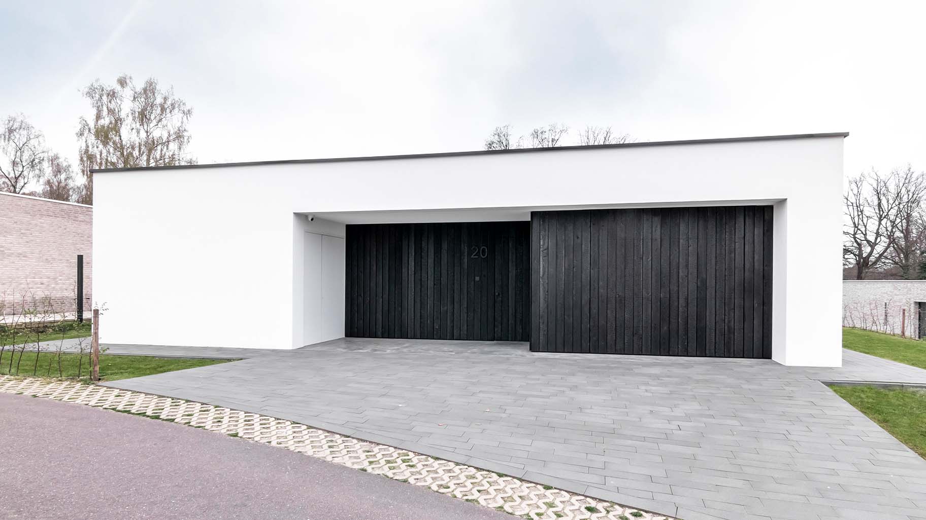 Moderne woning met Shou Sugi Ban houten garagedeur en voordeur, gelijk met de zwarte gevel