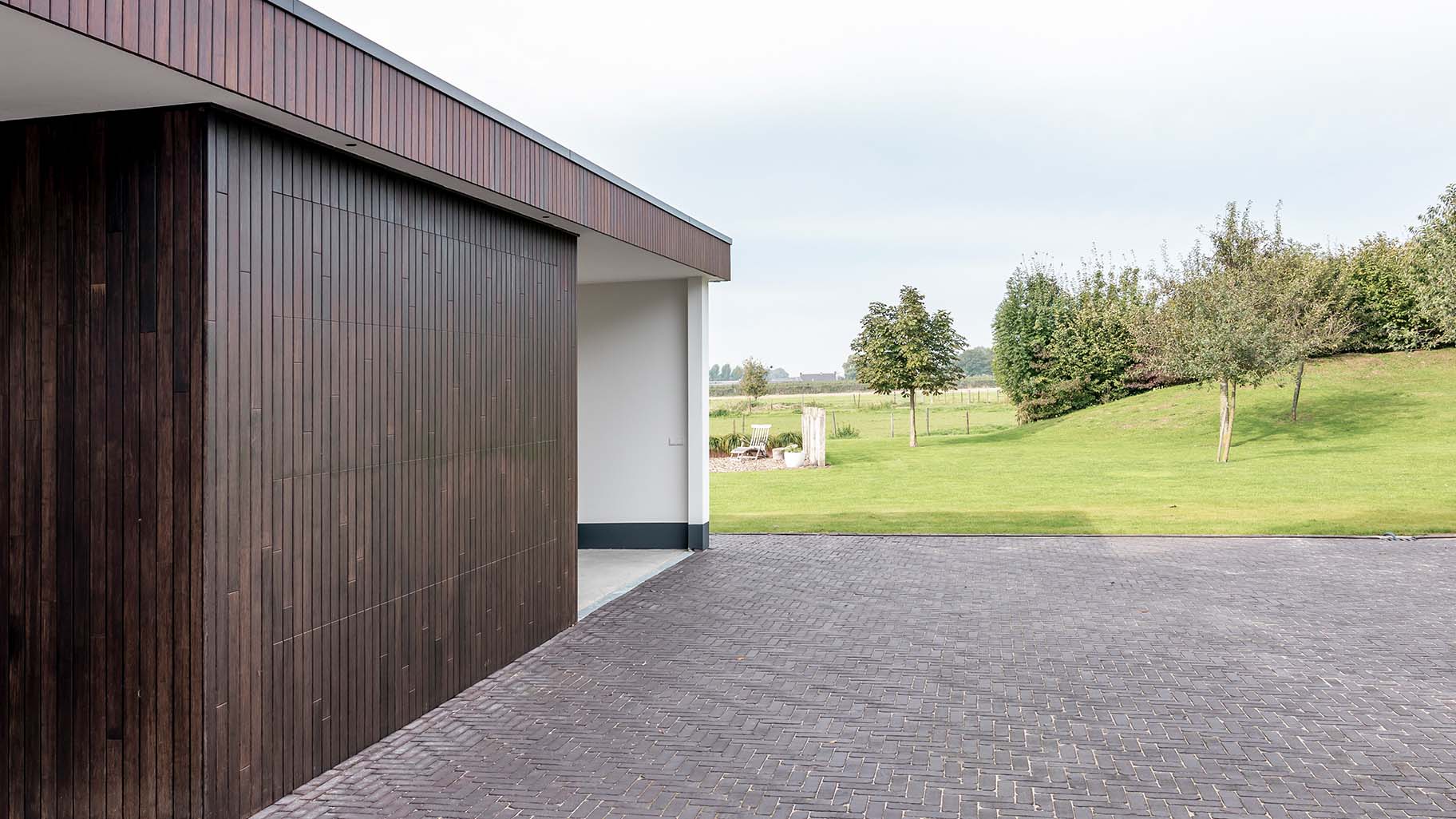 Carport met verticale sectionaaldeur van bamboe hout die een warme uitstraling