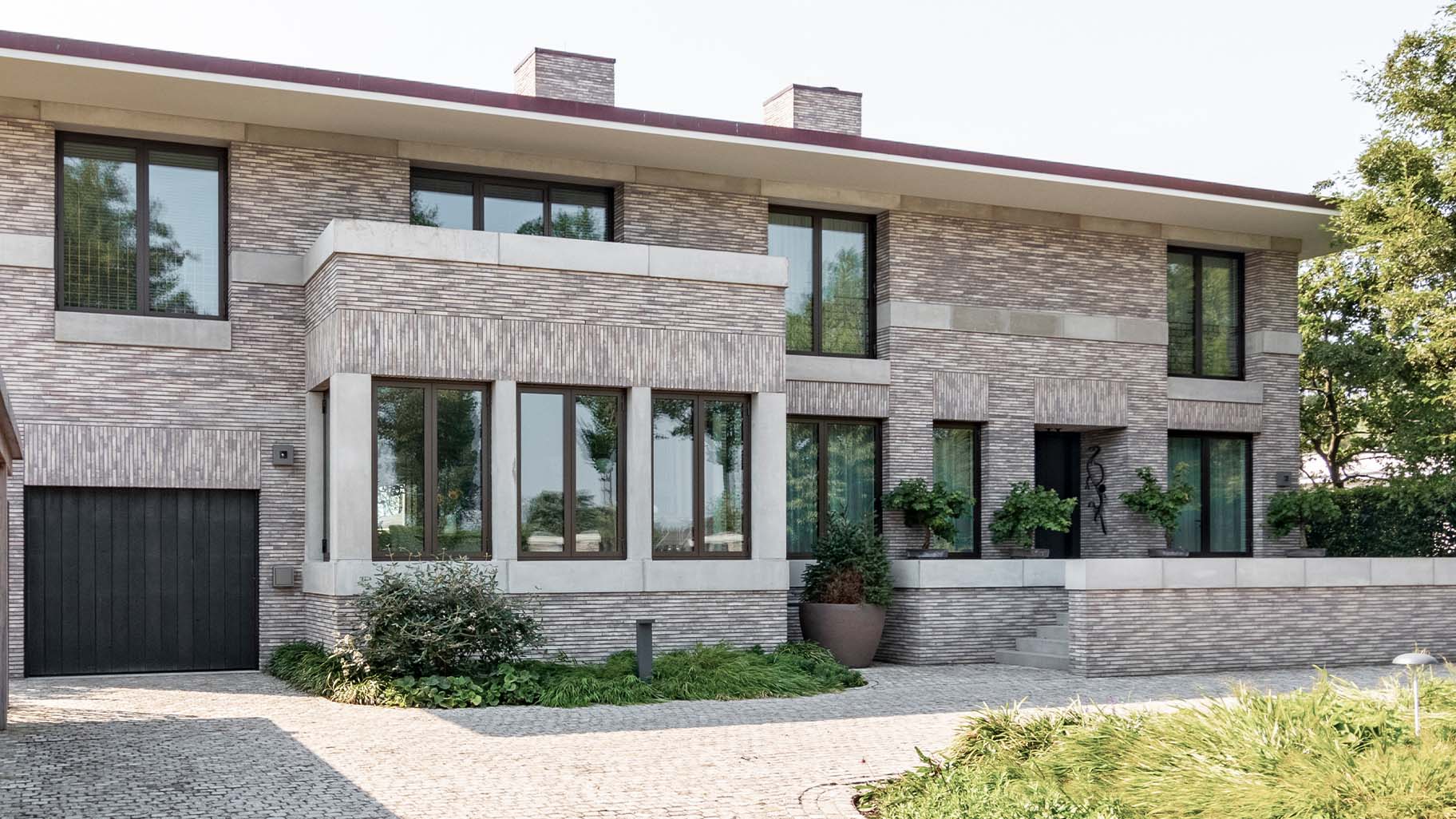 De Shou Sugi Ban garagedeur is achter de dag geplaatst, waardoor hij harmonieus opgaat in de gevel en de architectuur van de woning versterkt