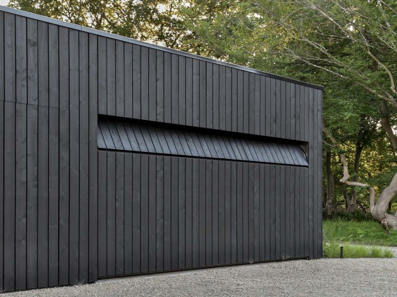 Dubbele houten garagedeur door Different doors gemaakt in de gevel