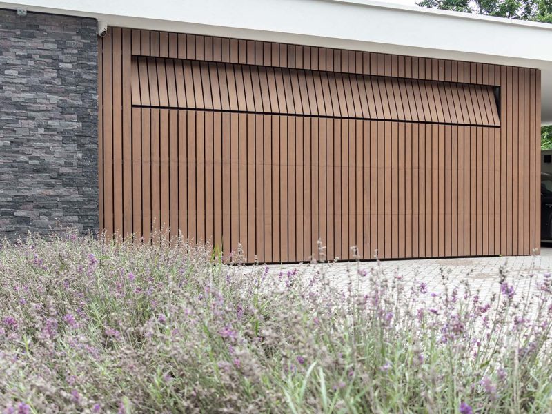 houten sectionaaldeur met verticale latten in warme bruintinten, passend bij de gevelbekleding