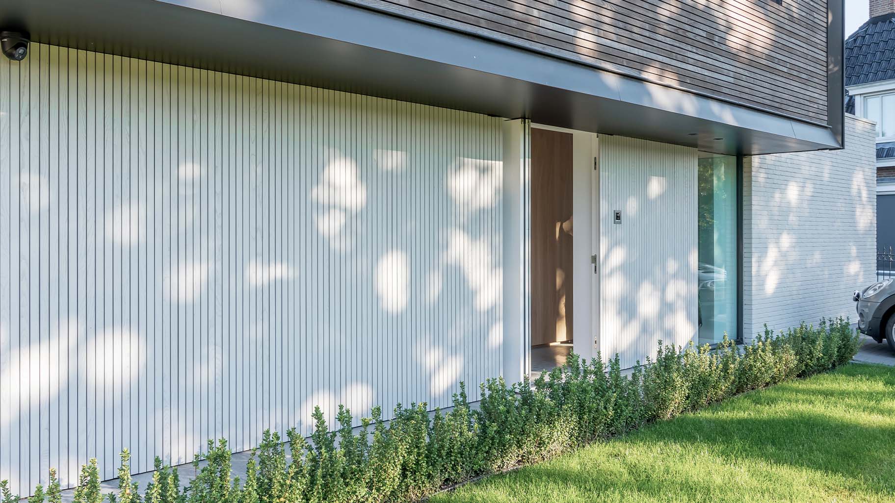 De taatsdeur als voordeur is gelijk met de gevel geplaatst waardoor deze volledig opgaat in het geheel