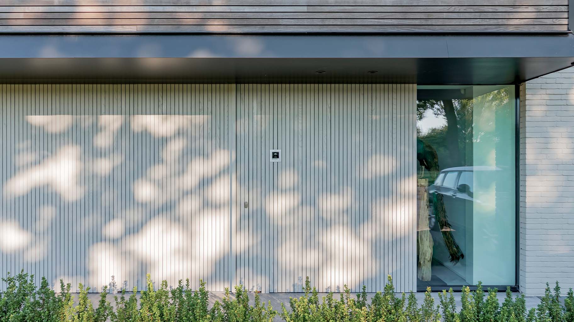 Woning met een houten taatsdeur als voordeur en een houten garagedeur
