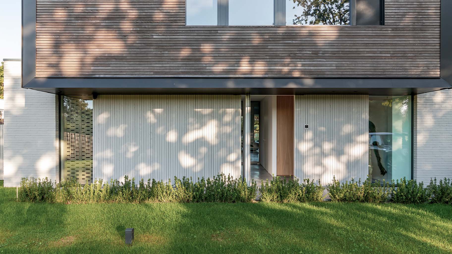Woning met een houten taatsdeur als voordeur en een houten garagedeur
