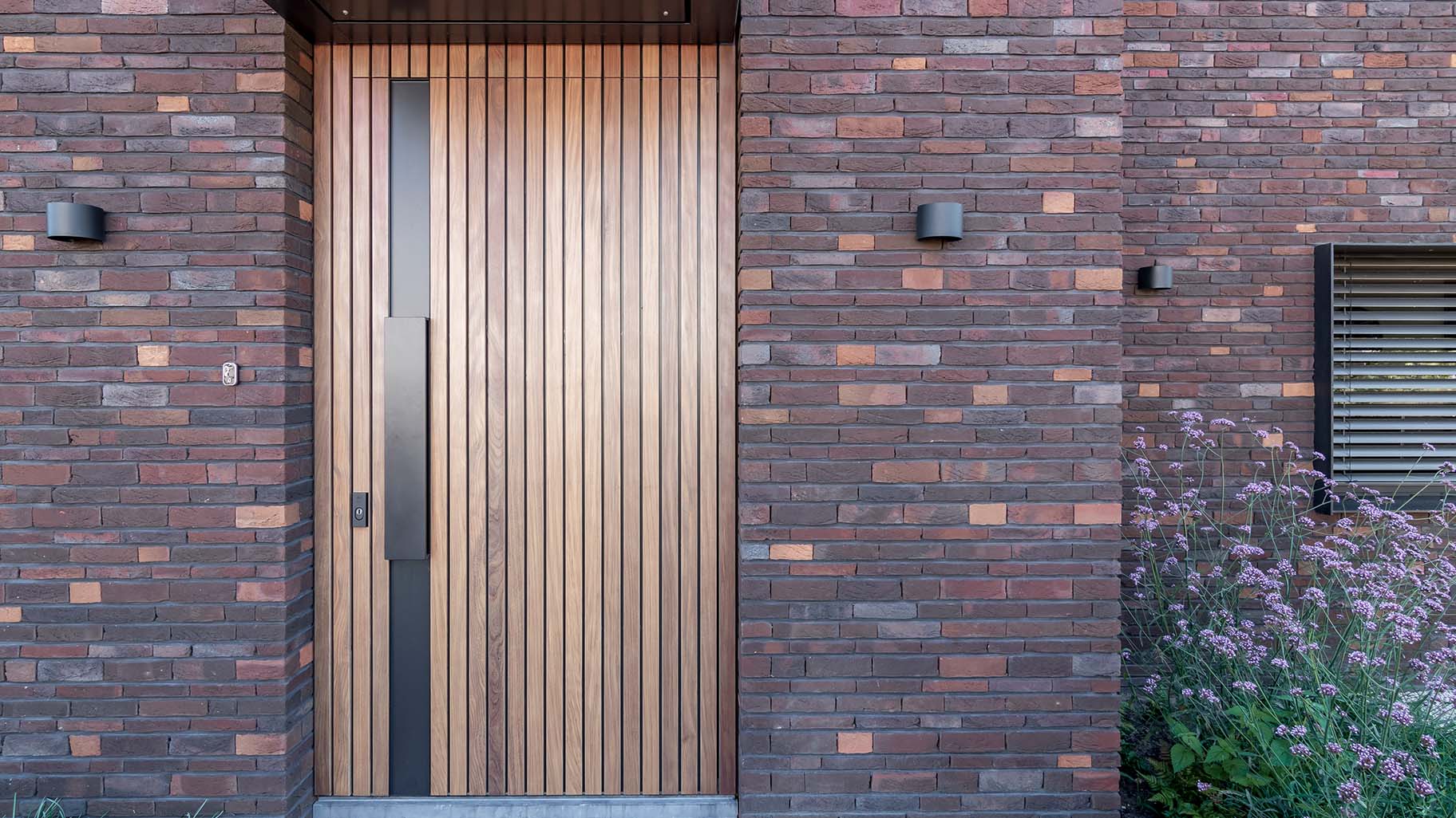 Taatsdeur als voordeur met hout bekleed en zwarte greep