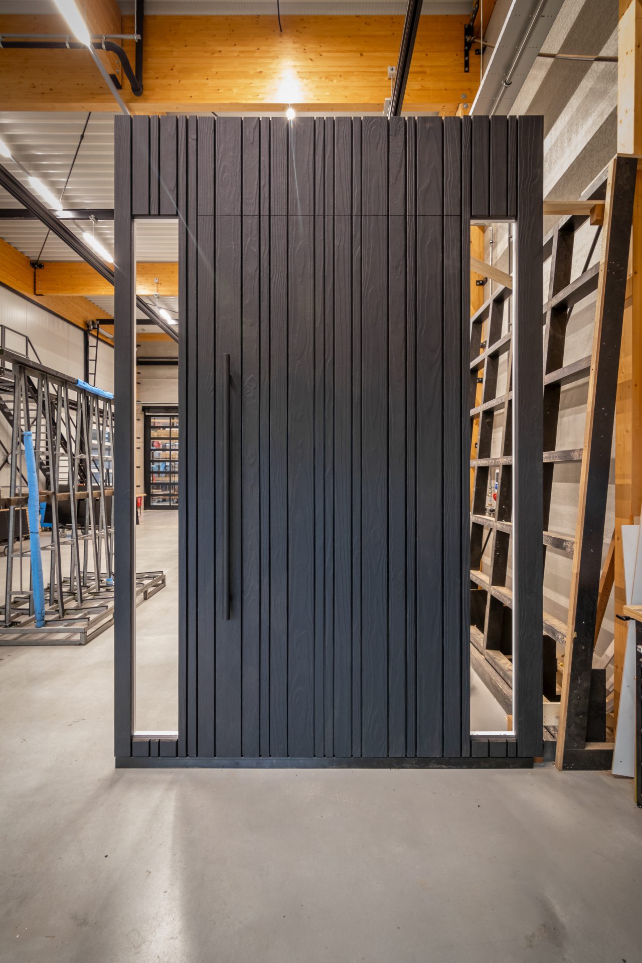 Exclusieve houten taatsdeur van Shou Sugi Ban hout, samen met zijlichten, gemaakt in moderne productiehal in Budel