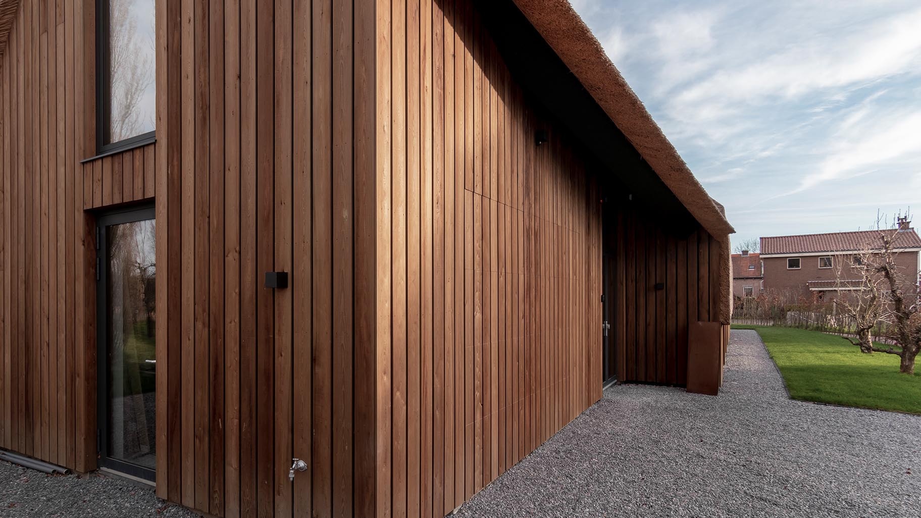 De houten garagedeur is gelijk met de gevel geplaatst, wat zorgt voor een onopvallende integratie in het ontwerp van de woning