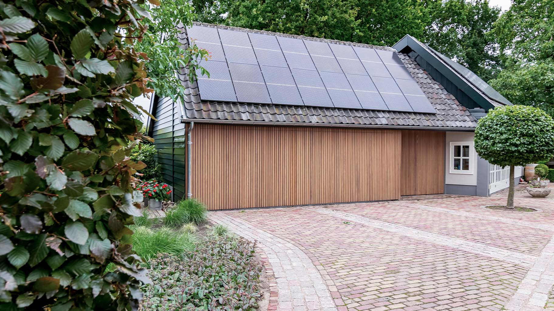 Zijwaartse houten garagedeur bij boerderij woning