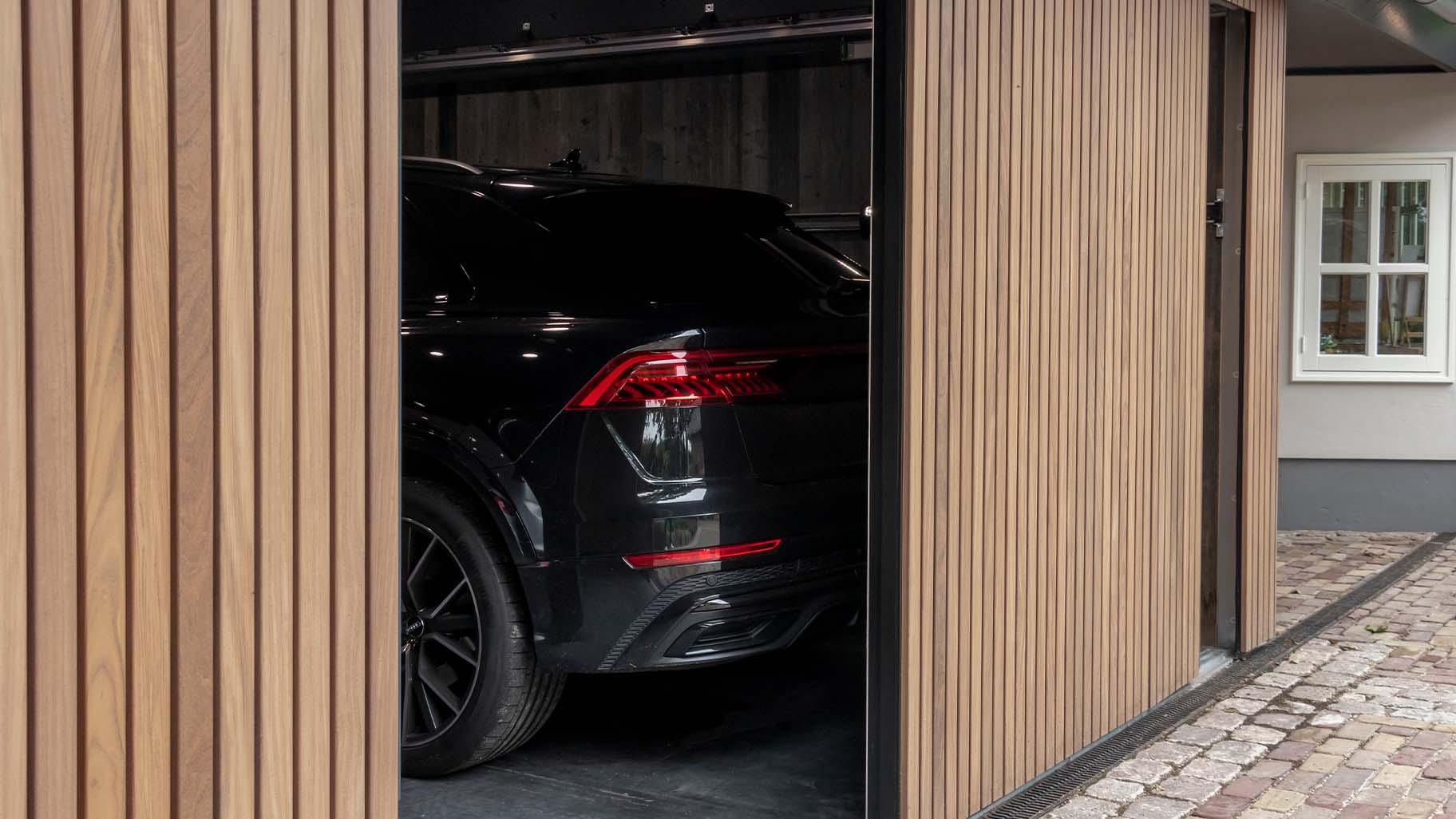 Dubbele zijwaartse houten garagedeur met auto's in de garage