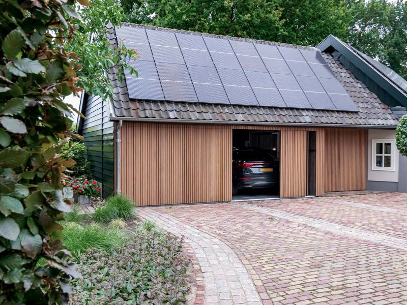 Zijwaartse houten garagedeur bij boerderij woning