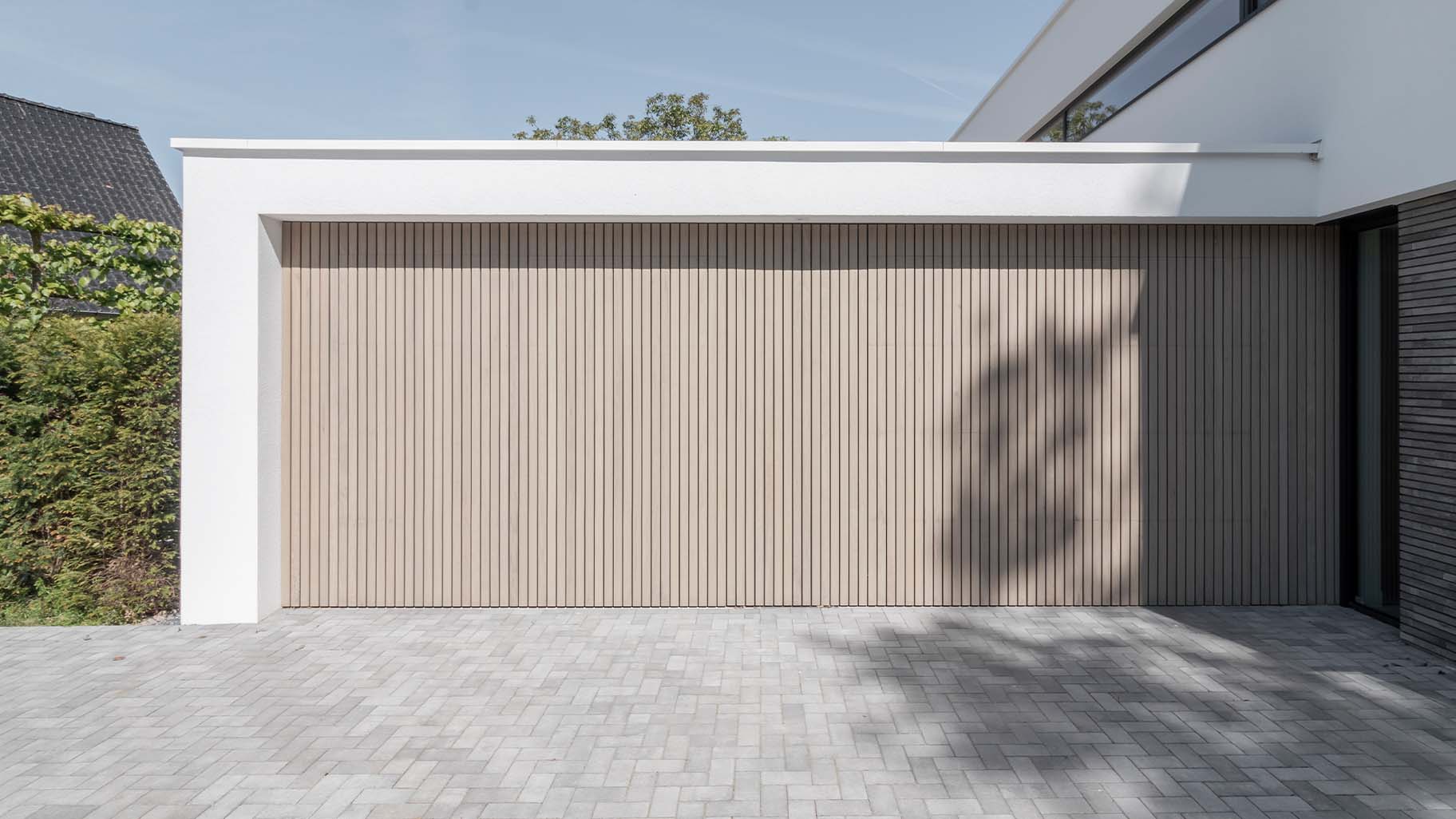 Frake houten garagedeuren bij moderne villa met gevelbekleding