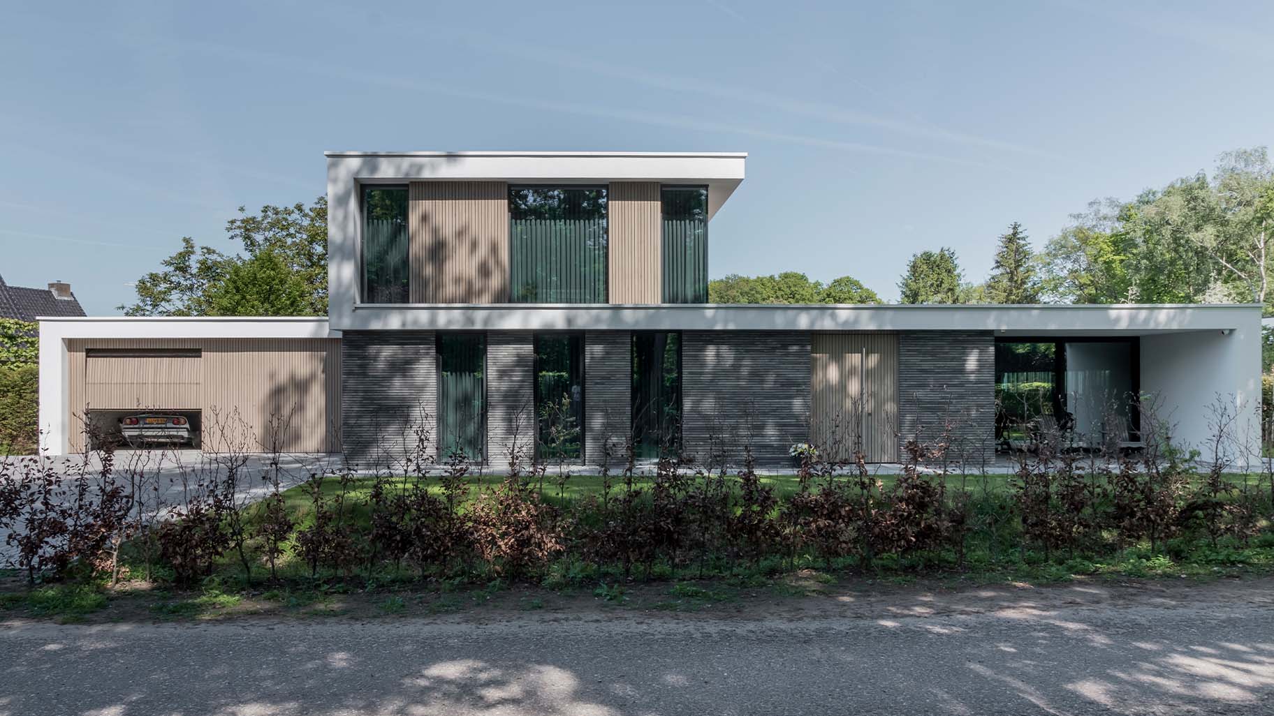 Frake houten garagedeuren bij moderne villa met gevelbekleding