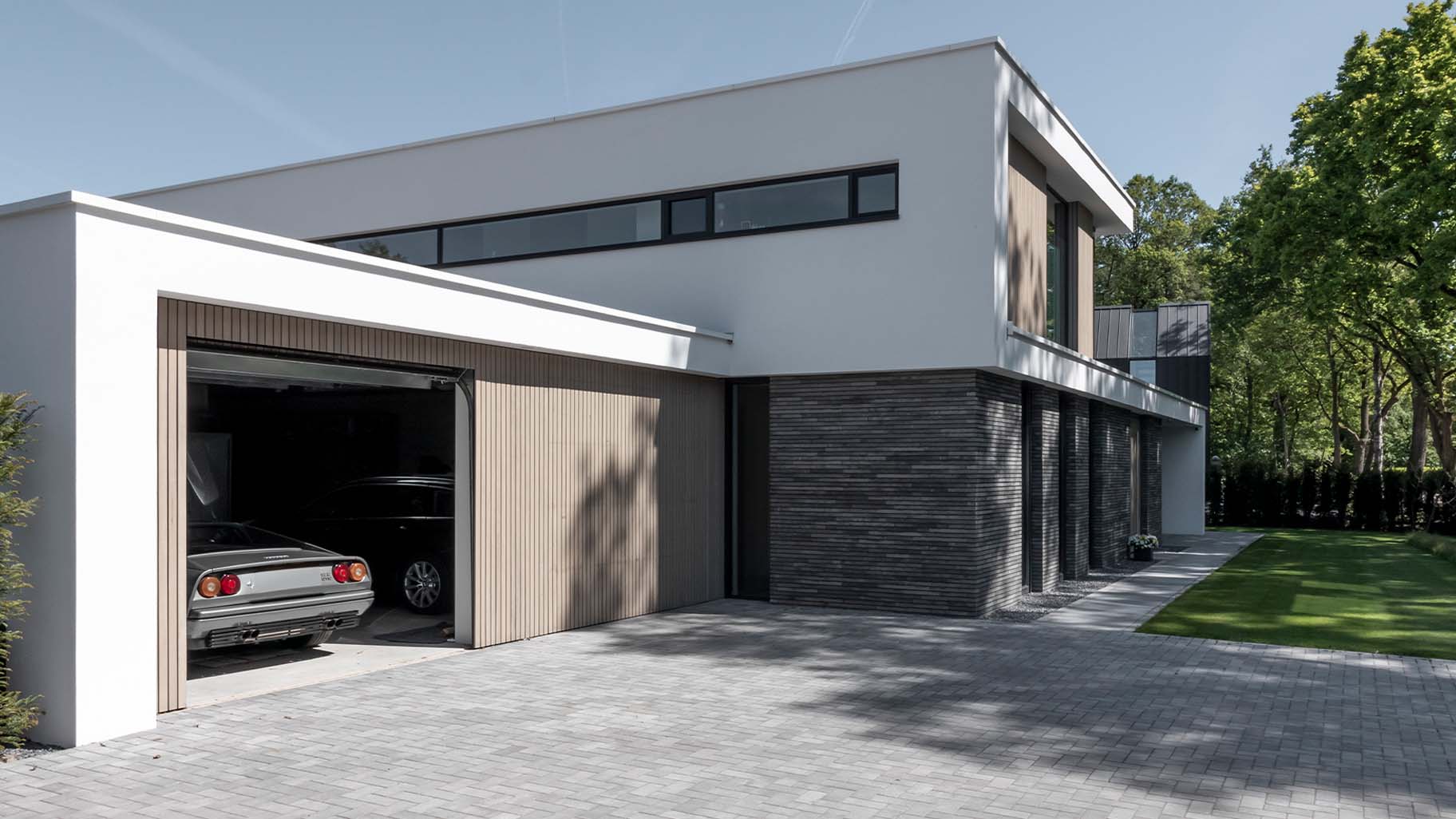 Frake houten garagedeuren bij moderne villa met gevelbekleding