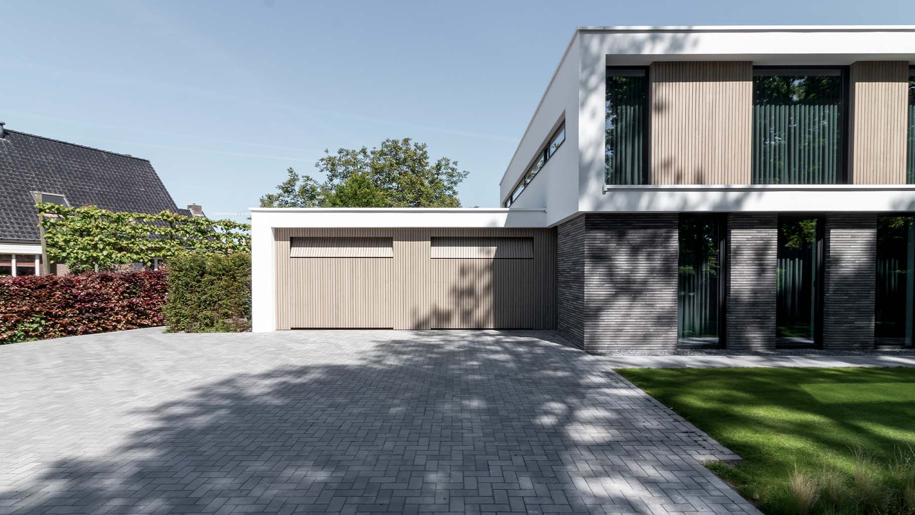 Moderne villa met twee frake houten garagedeuren in de garage