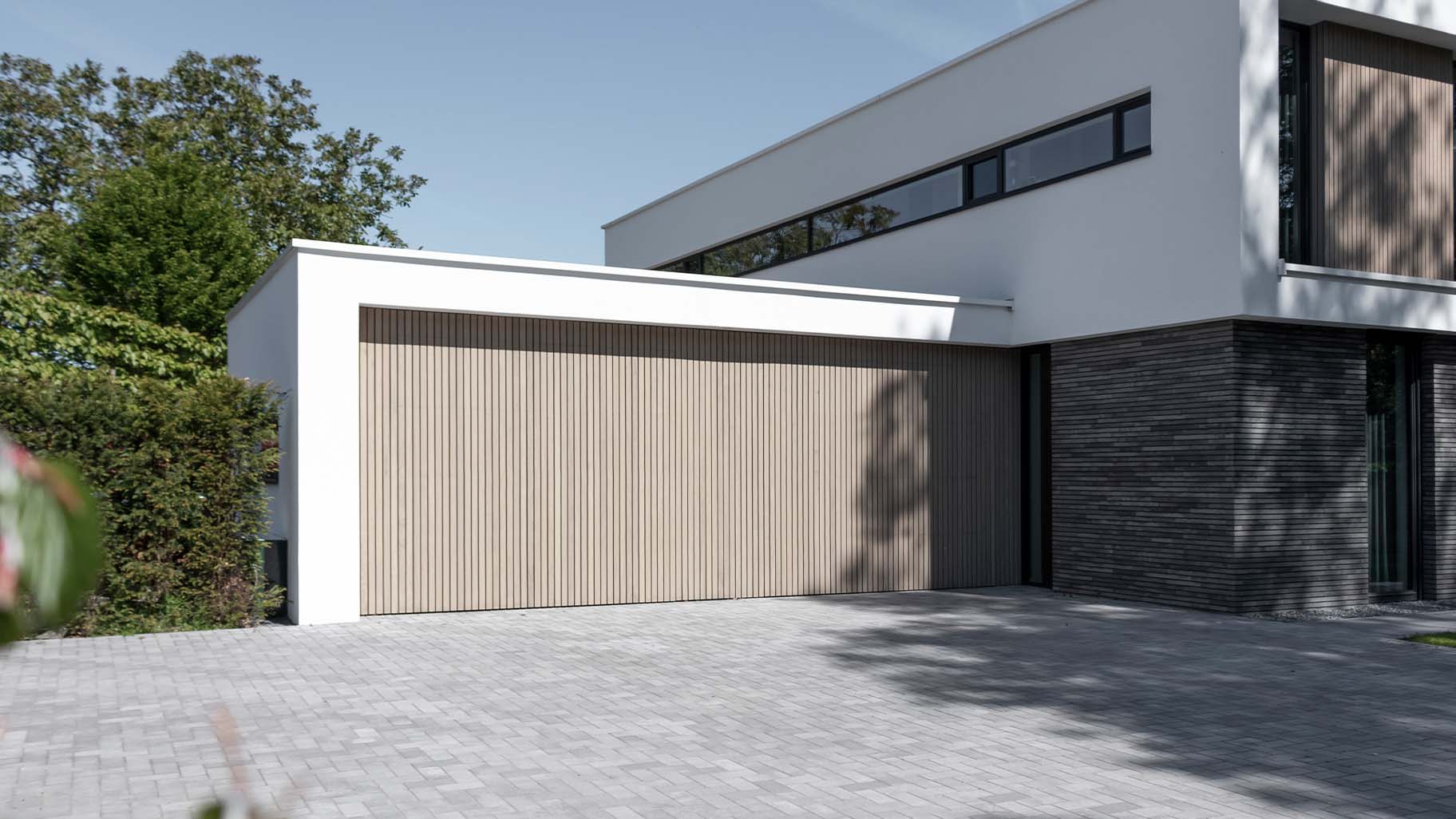 Moderne villa met twee frake houten garagedeuren in de garage
