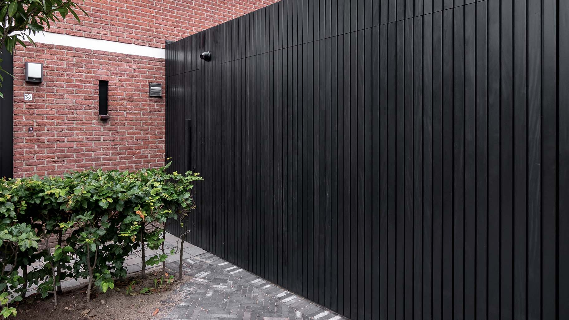 Op maat gemaakte zwarte houten zijwaartse garagedeur, gerealiseerd door Different Doors